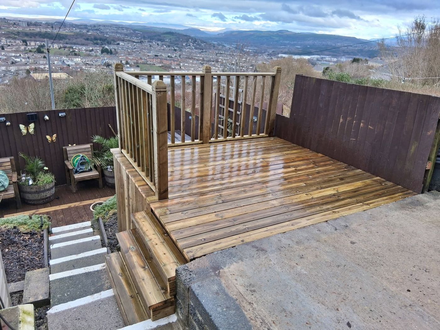 Raised timber decking with balustrade and steps in a garden