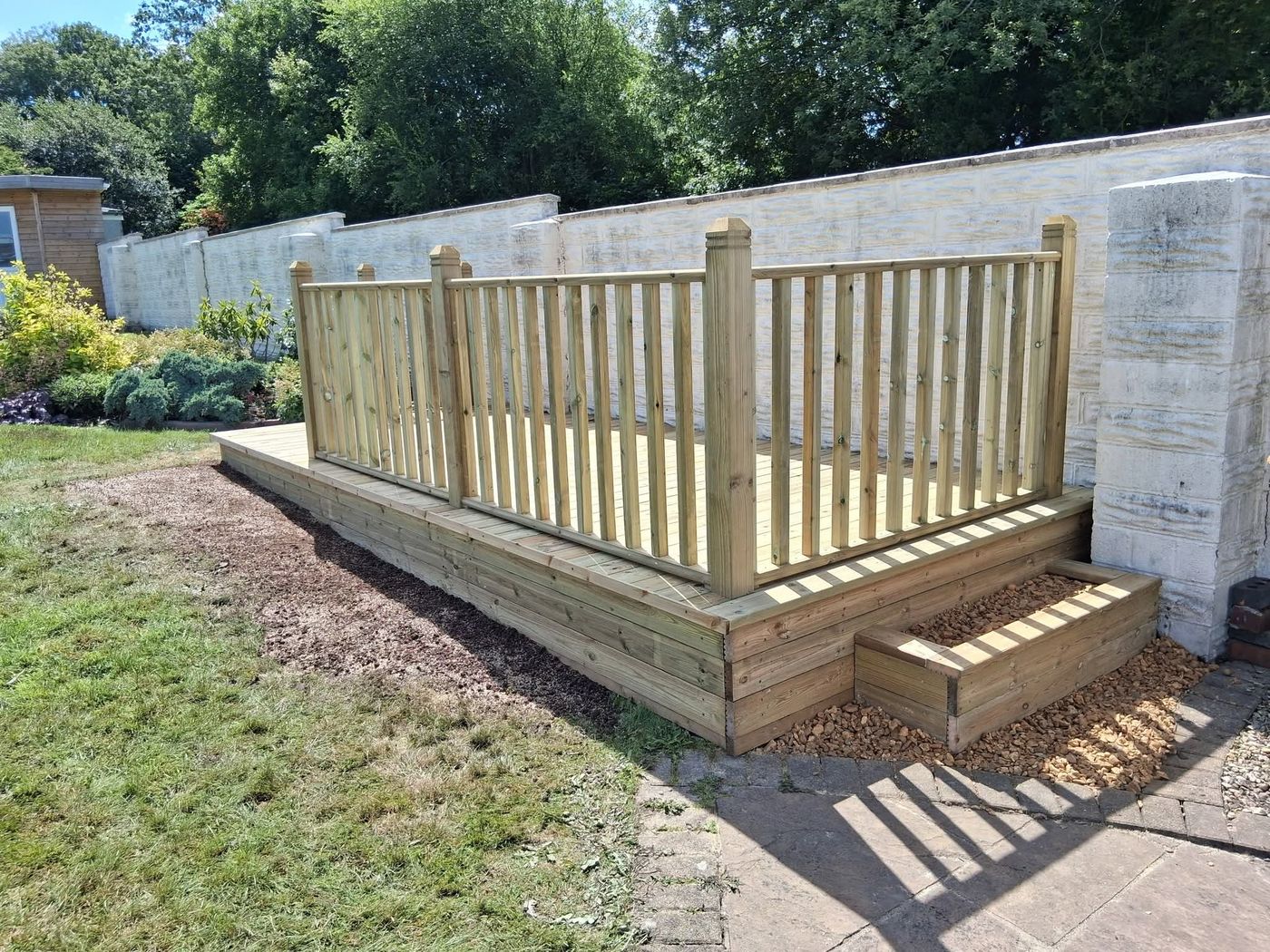 Raised timber decking with spindle balustrade beside a lawn