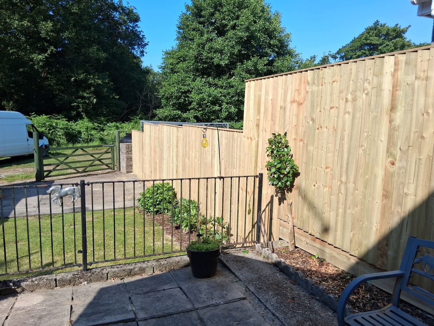 Tall timber close board fencing beside a garden path with a gate opening