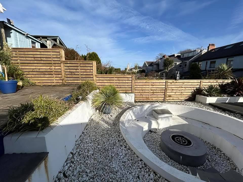 Horizontal timber slat fencing along a garden boundary with raised beds and gravel